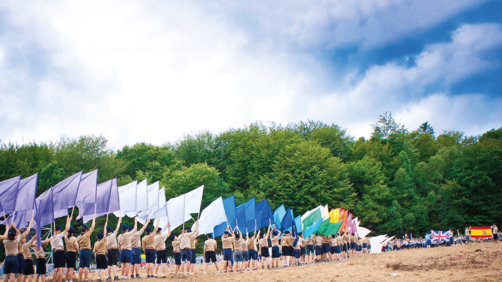Eurojam 2027. Gruppo di Scout in marcia e sventolano bandiere colorate